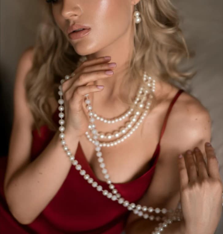 Woman wearing pearl necklace and earrings. Jewelry sales.